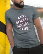Anti Social Spider Web Tee - model leaning on yellow-black pole, wearing Gray T-shirt, hand in pocket