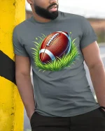 American Football T-Shirt - model leaning on yellow-black pole, wearing Gray T-shirt, hand in pocket