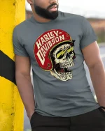 Vintage Biker Skull Helmet T-Shirt - model leaning on yellow-black pole, wearing Gray T-shirt, hand in pocket