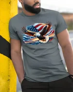 American Eagle USA Flag T-Shirt - model leaning on yellow-black pole, wearing Gray T-shirt, hand in pocket