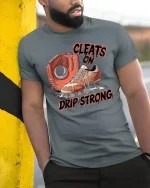 Baseball Cleats Drip Strong T-Shirt - model leaning on yellow-black pole, wearing Gray T-shirt, hand in pocket
