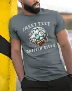 Sweet Feet Drippin’ Elite T-Shirt Funny Soccer Style - model wearing grey tee, leaning on column
