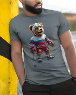 Funny Hockey Bear Graphic Tee With Playful Sports Style - model wearing grey tee, leaning on column