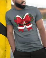 Funny Christmas Bow Graphic Tee With Santa Belt Style Design - model wearing grey tee, leaning on column