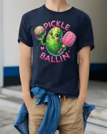 Pickle Ballin Funny Pickleball Cartoon Graphic T Shirt - model wearing navy tee with hands in pockets