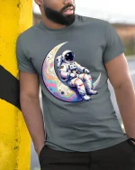 Astronaut Sitting On Moon T Shirt Cosmic Dream Art - model wearing grey tee, leaning on column
