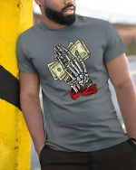 Skeleton Hands Money Prayer Graphic T Shirt Street Hustle Art - model wearing grey tee, leaning on column