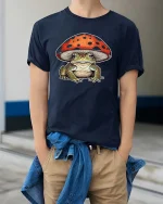 Cute Frog Under Mushroom Graphic T Shirt Whimsical Nature Art - model wearing navy tee with hands in pockets