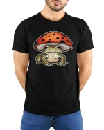 Cute Frog Under Mushroom Graphic T Shirt Whimsical Nature Art - model wearing black tee with hands behind back