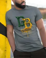 Green Gold Drip Letters Football Fan Style Graphic Tshirt - model wearing grey tee, leaning on column